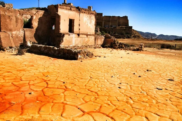 スペインのマザロンにある古い放棄された鉱山の乾燥した湖に堆積したカラフルなオレンジの堆積物 背景に古い廃屋 — ストック写真