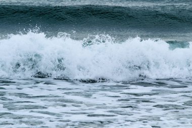 İspanya 'nın Alicante kentindeki La Marina plajında kışın bulutlu gökyüzünün altında dalgalı deniz.
