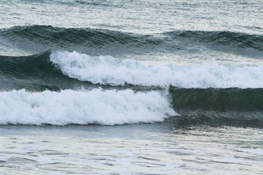 İspanya 'nın Alicante kentindeki La Marina plajında kışın bulutlu gökyüzünün altında dalgalı deniz.