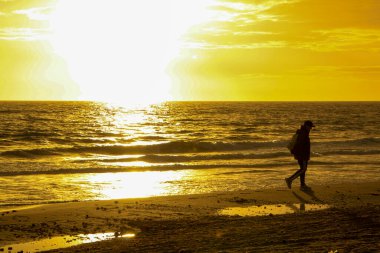 Arenales del Sol, Alicante, güney İspanya 'da, plajda pembe ve turuncu renklerle güzel bir gün doğumu. Ufka bakan kadın.