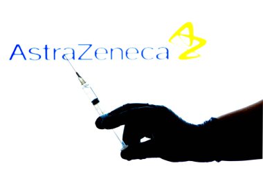 Madrid, İspanya - 2 Mayıs 2021 Şırınga ile Covid aşısını tutan eldiven. Arka planda Astrazeneca Laboratuvarı logosu