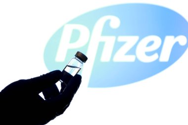 Madrid, İspanya - 2 Mayıs 2021: Beyaz arka planda covid-19 aşısı ve Pfizer laboratuvar logosu olan el ele tutuşma şişesi.