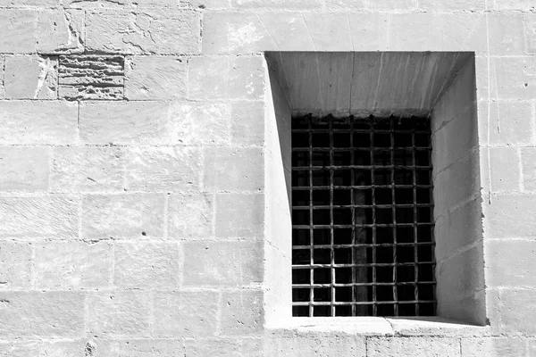 Window with wrought iron grille on the stone facade of Santa Maria church in Elche, Alicante, Spain