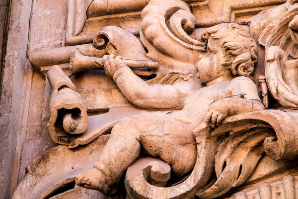 Elche, Alicante, Spain- May 5,2021: Beautiful Carved stone angel playing the trumpet on the main facade of Santa Maria church in Elche, Alicante, Spain.
