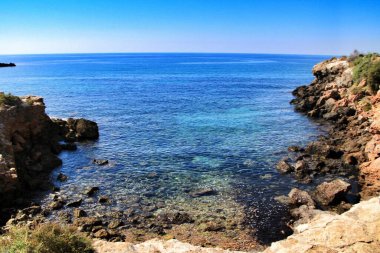Güneşli bir günde İspanya, Murcia, Cartagena 'daki Isla Plana köyünde kayaları, kayaları ve dağları olan güzel bir sahil.