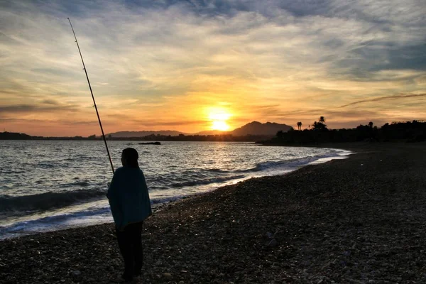 Fisherman at Sunset on Mojon beach in Isla Plana, Cartagena, Murcia,Spain.