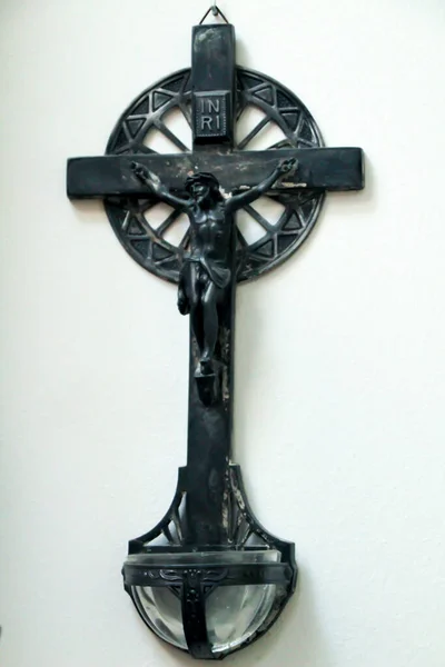 Beautiful and old holy water font with Jesus Christ on the cross