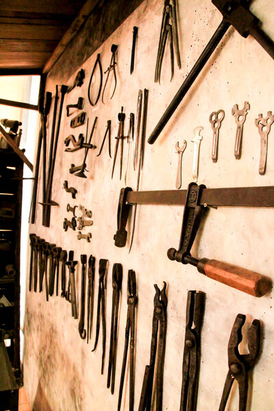 Old metal tools hanging on a wall of a workshop in Spain