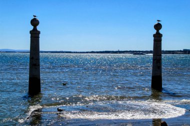 Baharın güneşli bir gününde Lizbon 'daki Tagus Nehri kıyısında Do Comercio Meydanı' nın sütunları. Zirvedeki martılar.