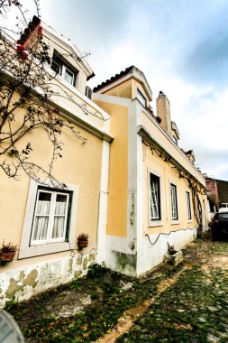 Lizbon, Portekiz - 6 Mart 2020: Portekiz 'de bulutlu bir günde görkemli cepheleri, pencereleri ve balkonları olan dar ve renkli sokaklar
