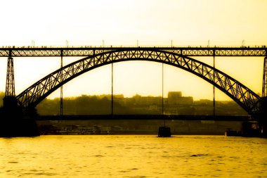 Günbatımında Porto 'daki Douro Nehri' nin suları üzerinde Dom Luis I adlı güzel ve devasa demir köprü.