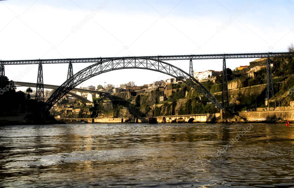 Beautiful and colossal iron bridges called Maria Pia and Ponte do Infante over the waters of the Douro River in Porto at sunset