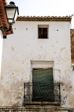 Altea, Alicante, İspanya 'da paslı balkonu ve yeşil körü olan eski bir ev cephesi.