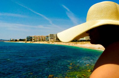 Woman in big white on Cap Negret beach on a sunny day of Spring in Altea, Alicante, Spain