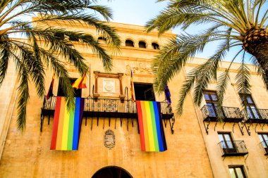Elche, Alicante, İspanya 'daki Uluslararası Gay Onur Günü için belediye binasının balkonunda asılı gökkuşağı bayrağı.