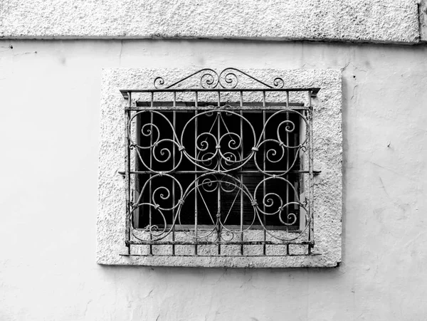 Old window on stone wall with rusty iron lattice in Alicante, Spain
