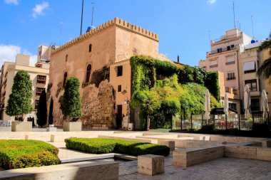 Elche, Alicante, İspanya - 2 Temmuz 2021: Calahorra Kulesi 'ni ziyaret eden turist mavi gökyüzü altındaki muhteşem dikey bahçesi ile İspanya' nın Alicante kentinde