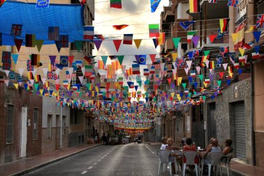 Santa Pola, Alicante, İspanya - 3 Eylül 2019: Santa Pola Caddesi Eylül ayındaki şenlikleri için renkli bayraklar ve çelenklerle süslenmiş.