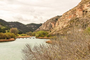 Tolosa rezervuarı Alcala del Jucar köyü, Albacete, İspanya 'da bitki örtüsü ve dağlarla çevrili.