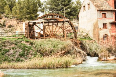 Eski ahşap su çarkı ve Cabriel Nehri Casas del Rio köyü, Albacete, İspanya 'ya gidiyor. Baston tarlası ve dağlar arasındaki manzara.