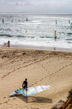 Lizbon, Portekiz- 20 Nisan 2020: Portekiz 'de bulutlu gökyüzünün altında Guincho sahilinde sörfçüler