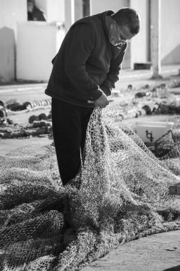 Santa Pola, Alicante, İspanya - 26 Kasım 2025: Balıkçı Santa Pola balıkçı köyünün limanındaki hasarlı ağları onarıyor