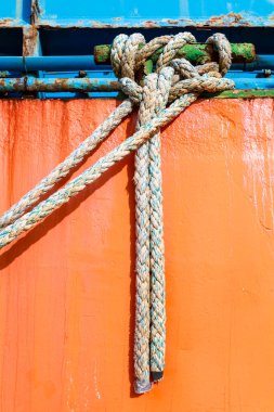 Halatlar Denia, Alicante, İspanya 'daki eski teknenin paslı turuncu yüzeyinde asılı.