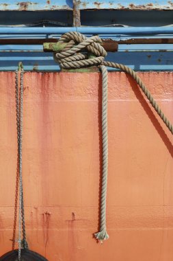 Halatlar Denia, Alicante, İspanya 'daki eski teknenin paslı turuncu yüzeyinde asılı.