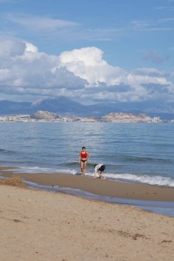 Alicante, İspanya - 14 Ocak 2026: Anne ve oğlu kışın İspanya 'nın güneyindeki Arenales del Sol kentinde sahilde