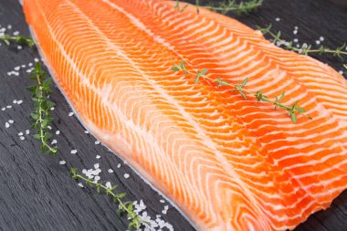 Yarım çiğ somon fileto, tuz ve kekik siyah ahşap masa, üst görünüm