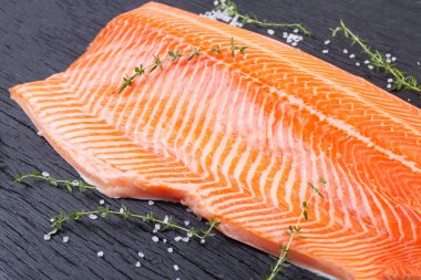 Yarım çiğ somon fileto, tuz ve kekik siyah ahşap masa, üst görünüm