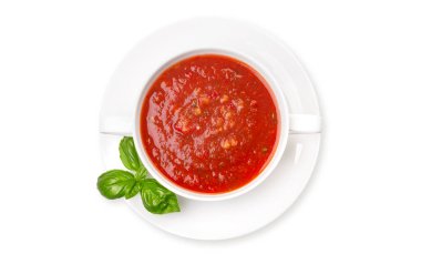 Beyaz bir tabakta gazpacho ve beyaz arka planda izole edilmiş fesleğen.