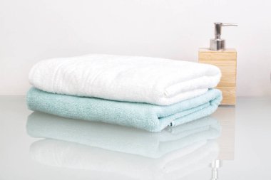 Banyo havluları ve cam bir masada sıvı sabun.