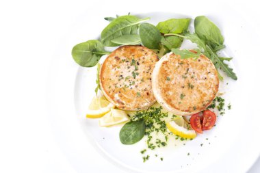 Beyaz tabakta somon pirzolası ve ıspanak salatası.