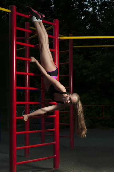 Female the gymnast trains on horizontal bars — Stock Photo, Image