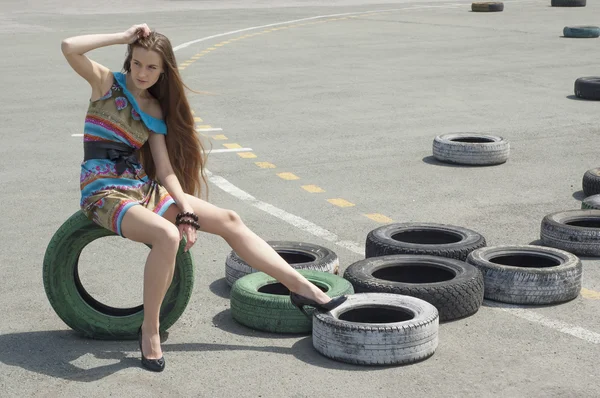 The girl in a beautiful dress sits on a wheel — Stock Photo, Image