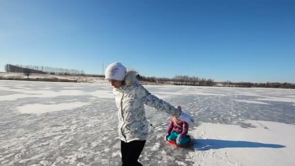 Chica trineo hermana en congelado lago — Vídeos de Stock
