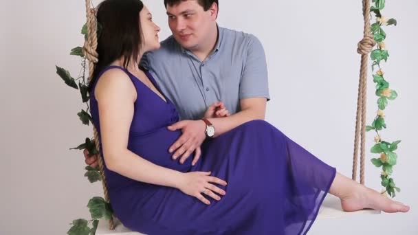 Femme enceinte avec son mari sur une balançoire . — Video