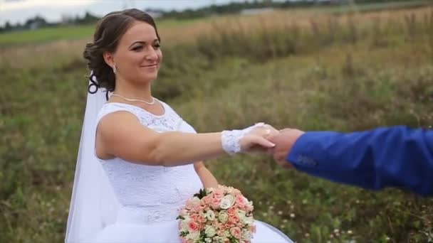 Счастливая красивая невеста и жених, гуляющие по полю — стоковое видео