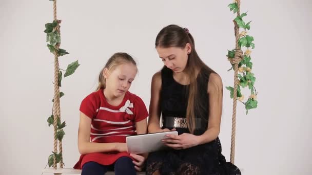 Girls sitting on swing with digital tablet — Stock Video