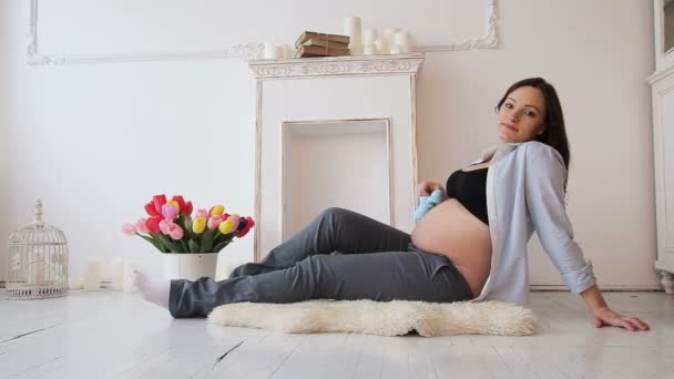 Schwangere hält Babyschuhe am Bauch — Stockvideo