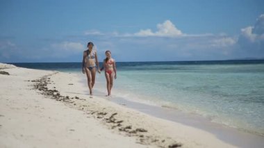 İki kız bir tropik sahilde yürümek
