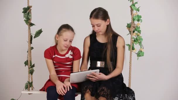 Meninas sentadas no balanço com tablet digital — Vídeo de Stock