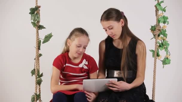 Mädchen sitzen mit digitalem Tablet auf Schaukel — Stockvideo