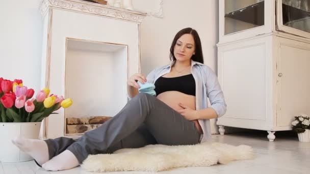 Zwangere vrouw met baby schoenen op haar buik — Stockvideo