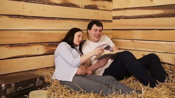 Pregnant woman and her husband reading book. — Stock Video