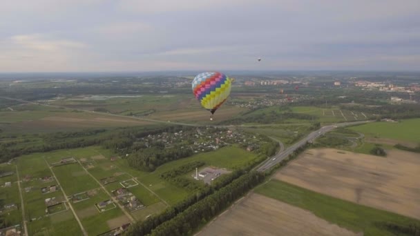 Varmluftsballonger i himlen över ett fält. Flygfoto — Stockvideo