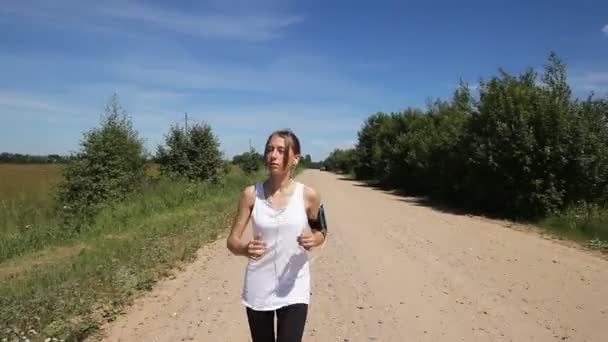 Chica corre en la carretera en un campo . — Vídeos de Stock