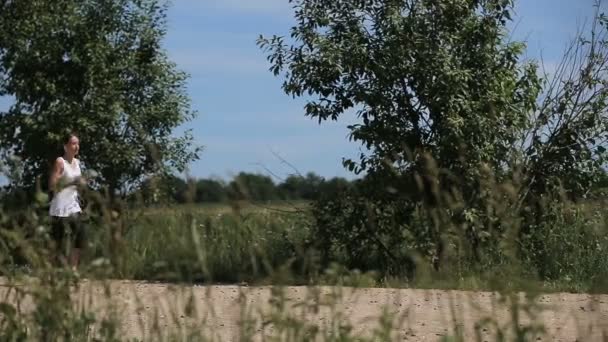 Chica corre en la carretera en un campo . — Vídeo de stock