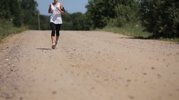 Chica corre en la carretera en un campo . — Vídeos de Stock